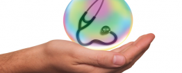 A mão de uma pessoa apoia uma bolha de sabão que reflete as cores do prisma. Dentro dela há um estetoscópio.