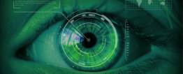 Foto em tons de verde de um olho. Sobre a íris há um círculo digital e do centro da pupila saem informações em forma de texto e mapa.